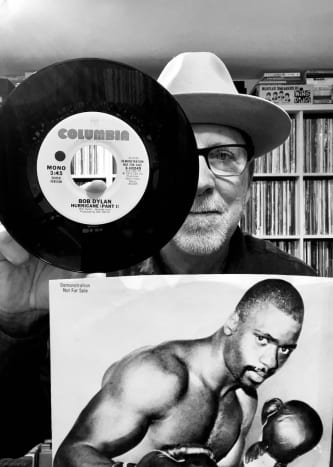 In photo: YouTube content creator and dedicated music collector - Norman "Mazzy" Maslov - from his music library in Seattle, WA, with a promotional mono copy of Dylan's "Hurricane" including original picture sleeve