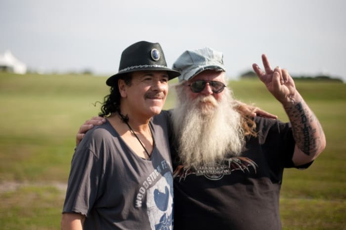 Before his sold out show Carlos Santana poses at the site of the 1969 Woodstock festival at Bethel Woods Center for the Arts, with Duke Devlin Site Intrepretor at Bethel Woods. Photo courtesy of Michael Bloom for Bethel Woods.