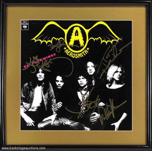 A fully band signed Aerosmith 'Get Your Wings' LP cover from 1974, featuring the autographs of Steven Tyler, Joe Perry, Tom Hamilton, Joey Kramer and Brad Whitford. All signatures are nicely done with a gold marker. The album cover is matted and housed in a 16 1/2 x 16 1/2 inch frame. Excellent condition. From the the private collection of David Frangioni.