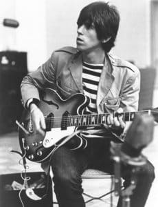 Guitarist Keith Richards of The Rolling Stones sits on a chair in a recording studio and strums his Epiphone guitar in 1966. (Photo by Michael Ochs Archives/Getty Images).