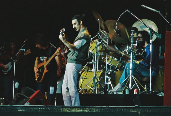 Frank Zappa performs on stage in 1978 with band members (L-R) Denny Walley, Arthur Barrow, Ike Willis (patially hidden) and drummer Vinnie Colaiuta. (Photo by Pete Still/Redferns)