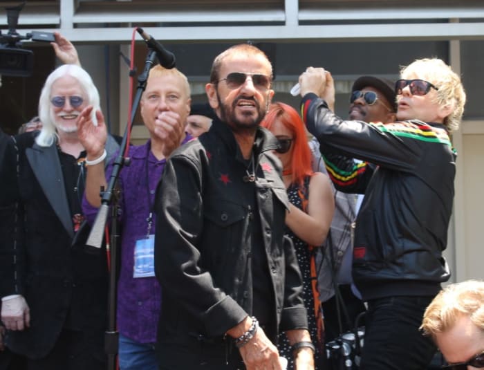 Ringo and friends (including son Zak Starkey, far right) toss "Peace & Love" wristbands into the crowd
