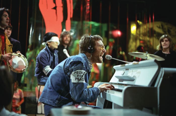 John Lennon performing “Instant Karma” on Top of the Pops, February 11, 1970, with Yoko Ono wearing a blindfold and bassist Klaus Voormann behind Ono. Photo by Ron Howard/Redferns